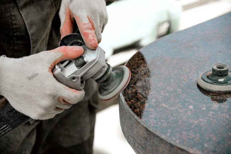 polishing a marble stone with an angle grinder with a working man in gloves