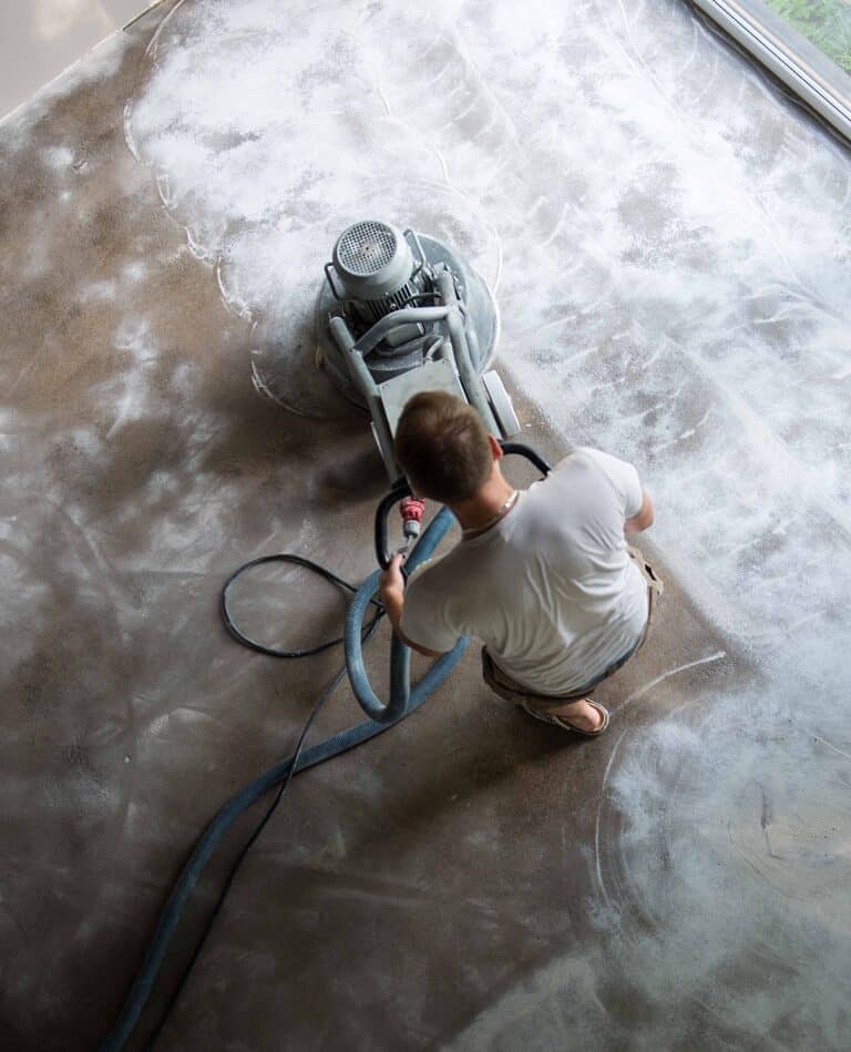 Construction worker in a family home living room that grind the concrete surface before applying epoxy flooring.Polyurethane and epoxy flooring.Concrete grinding.